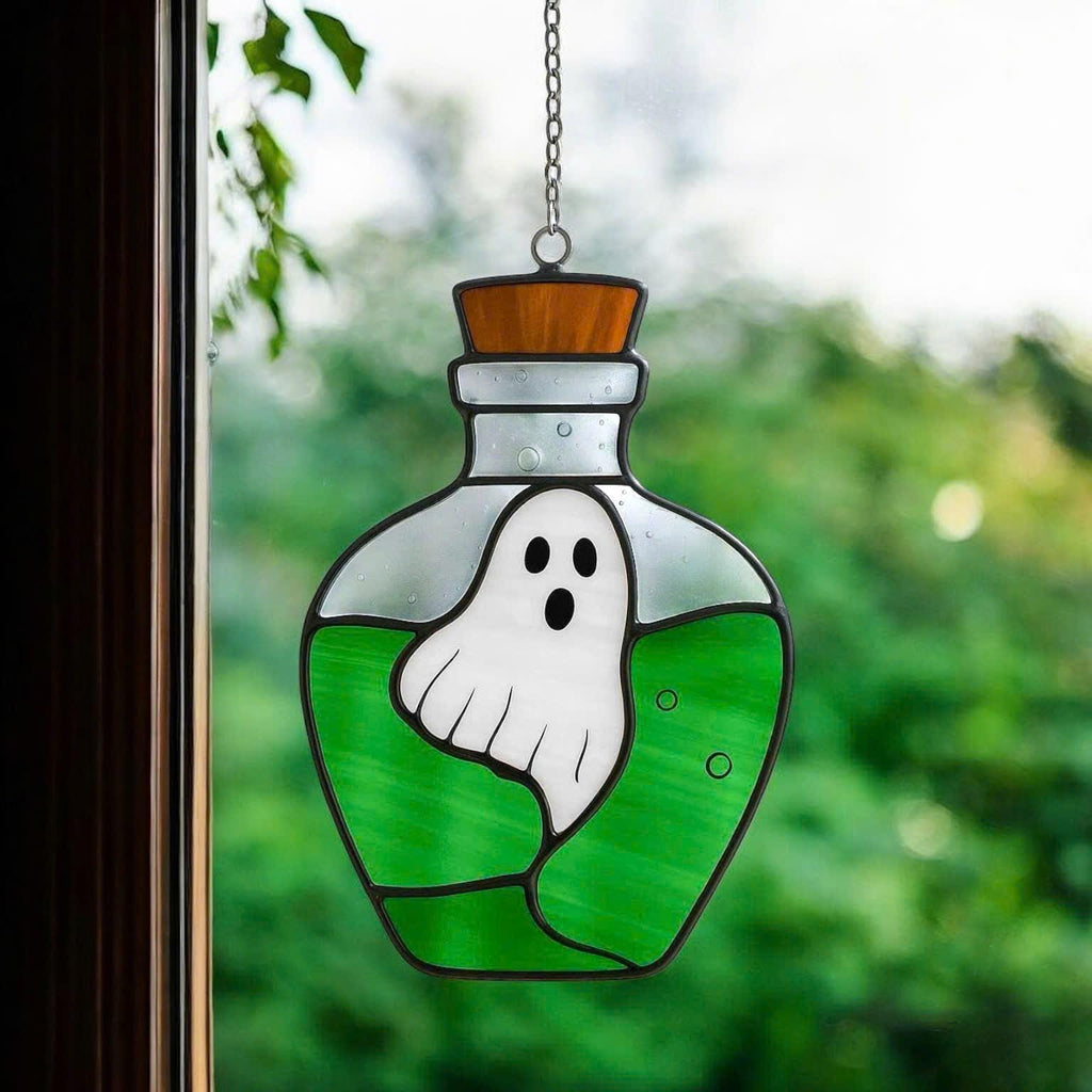 Handcrafted stained glass suncatcher featuring a ghost inside a purple potion bottle, real glass cut and soldered by hand, sunlight shining through for magical Halloween window decor.
