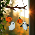 Halloween stained glass ghost and pumpkin suncatcher glowing in sunlight on window.