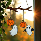 Halloween stained glass ghost and pumpkin suncatcher glowing in sunlight on window.