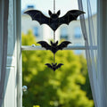 Handmade stained glass bat suncatcher hanging by a window, glowing in sunlight, whimsical Halloween home decor.