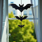 Handmade stained glass bat suncatcher hanging by a window, glowing in sunlight, whimsical Halloween home decor.