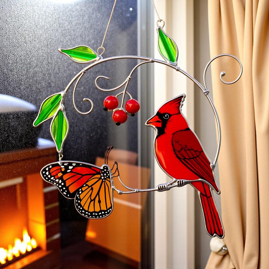 Close-up of the red cardinal stained glass ornament with a backdrop of snow falling outside the window.