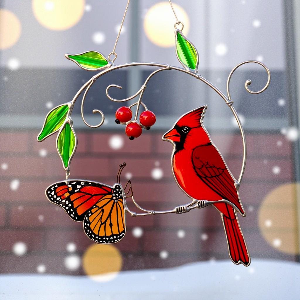 Cardinal ornament with cherries hanging in front of a snowy scene, adding festive cheer to the window.