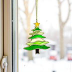 Christmas tree suncatcher (Style #2, lime green glass) hanging in a window overlooking a snowy winter scene.