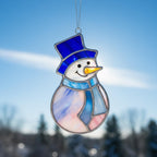 Close-up of the stained glass snowman (Style #1) standing upright in deep, fluffy snow.