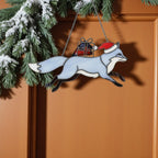 Blue stained glass fox with Santa hat carrying gift, handmade Christmas suncatcher.