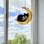 Stained glass cat moon suncatcher hanging above white bed, minimal bedroom wall decor