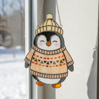 Smiling penguin in beige sweater stained glass ornament, cozy handmade winter home decoration.