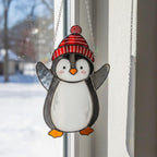 Penguin with yellow hat and coat, stained glass handmade ornament glowing in winter sunlight.