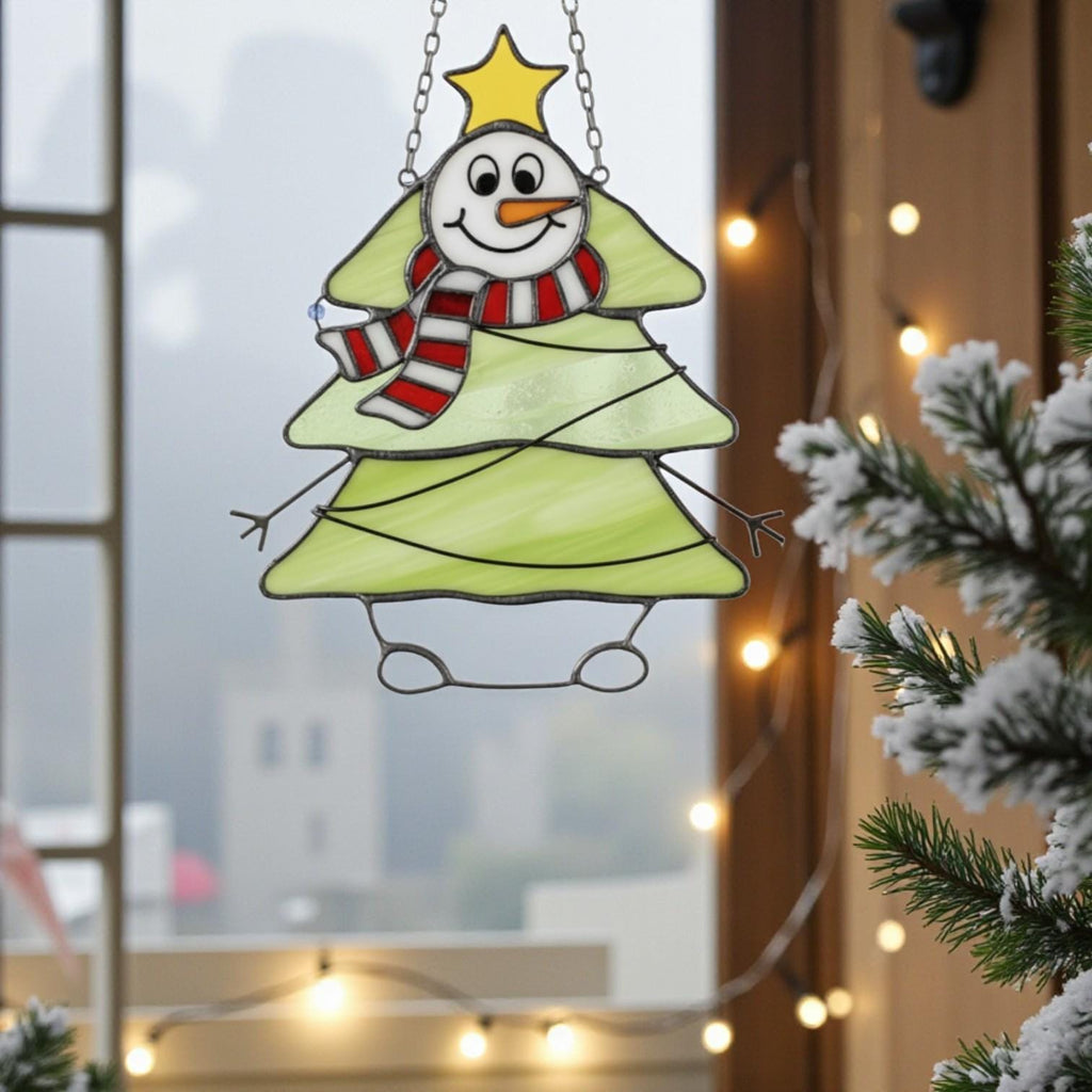 Snowman tree stained glass ornament glowing with winter sunlight on window sill.