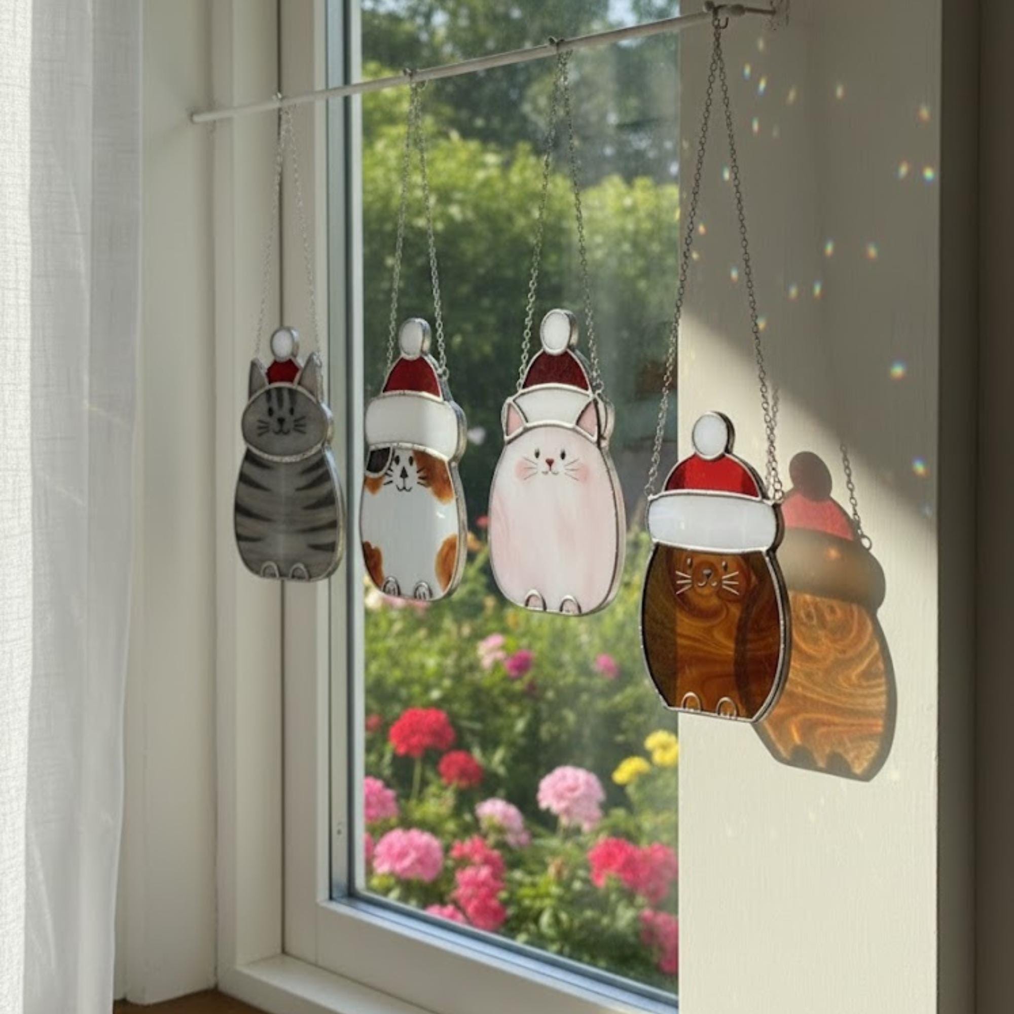 Christmas window with hanging cat ornaments and snow background – cozy handmade scene.