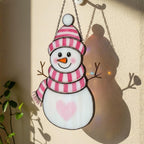 Violet and red handmade snowman ornaments hanging together – festive stained glass window art.
