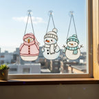 Hands holding stained glass snowman suncatcher under sunlight – winter handmade gift idea.
