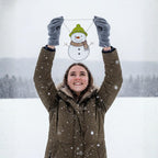 Woman lifting stained glass snowman ornament in snow – holiday winter suncatcher decor idea.