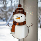 Brown hat snowman ornament glowing in sunlight – handmade stained glass gift for winter.