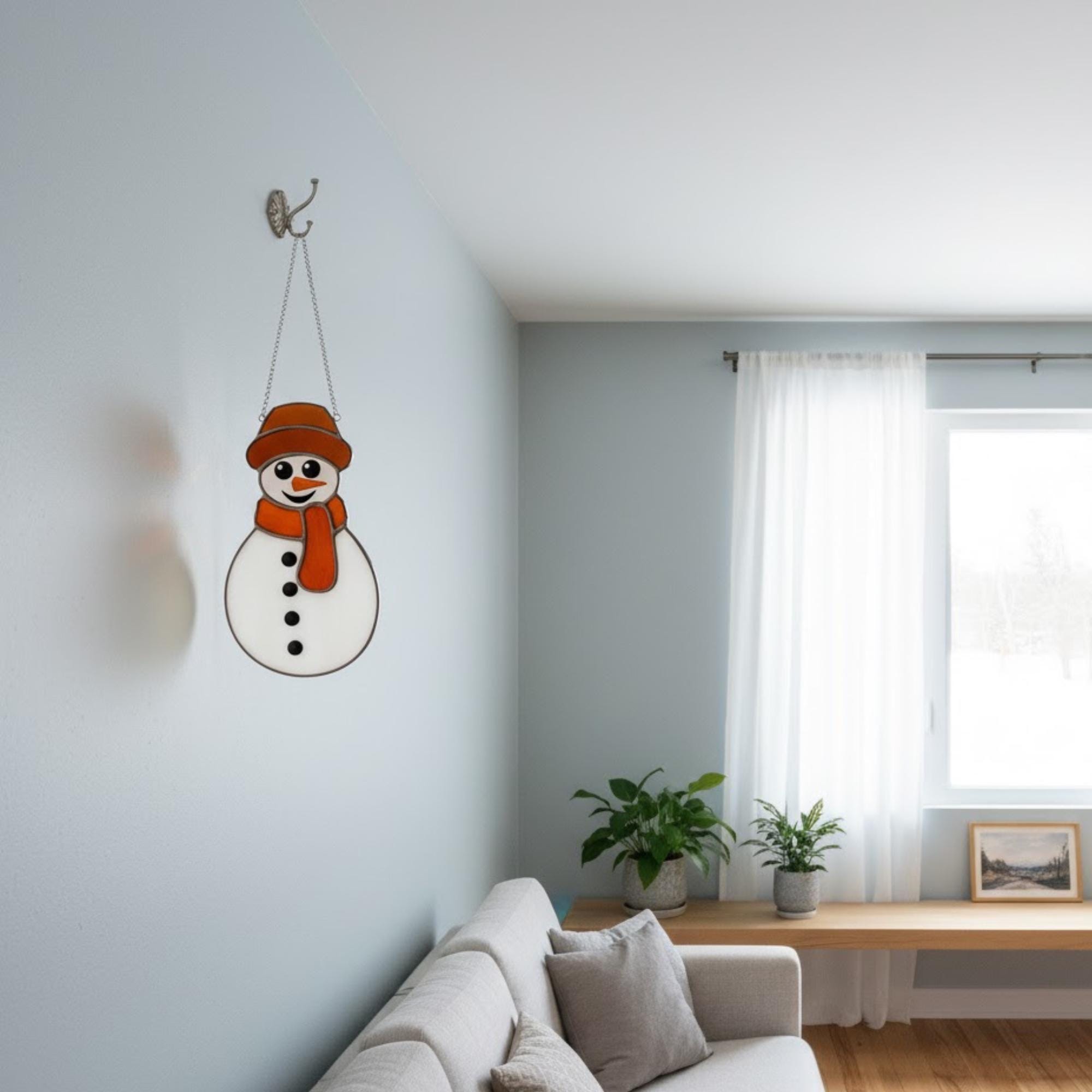 Trio of snowman ornaments hanging on snowy pine tree – outdoor Christmas stained glass decoration.