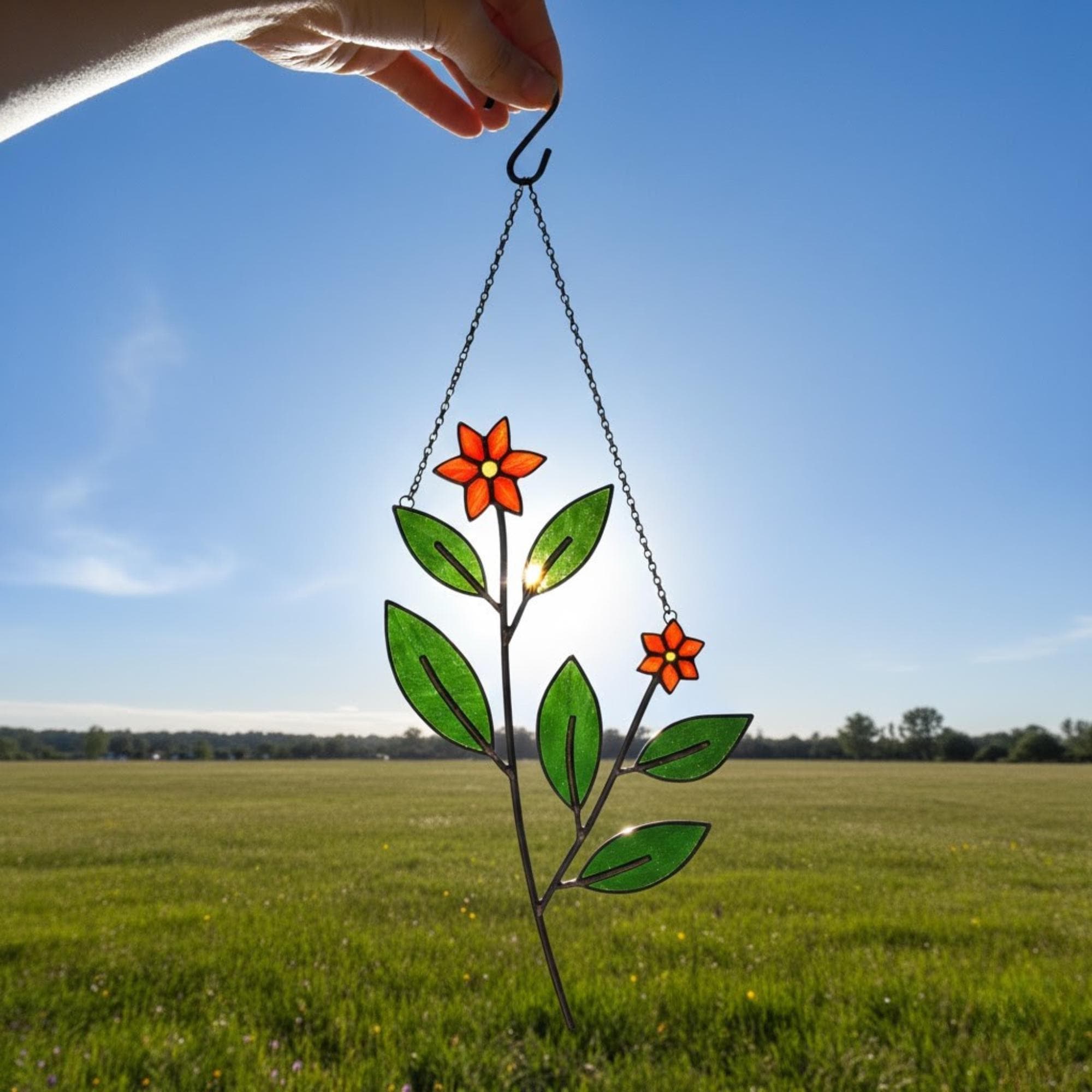 Hanging stained glass leaf ornament with sunlight casting beautiful reflections.