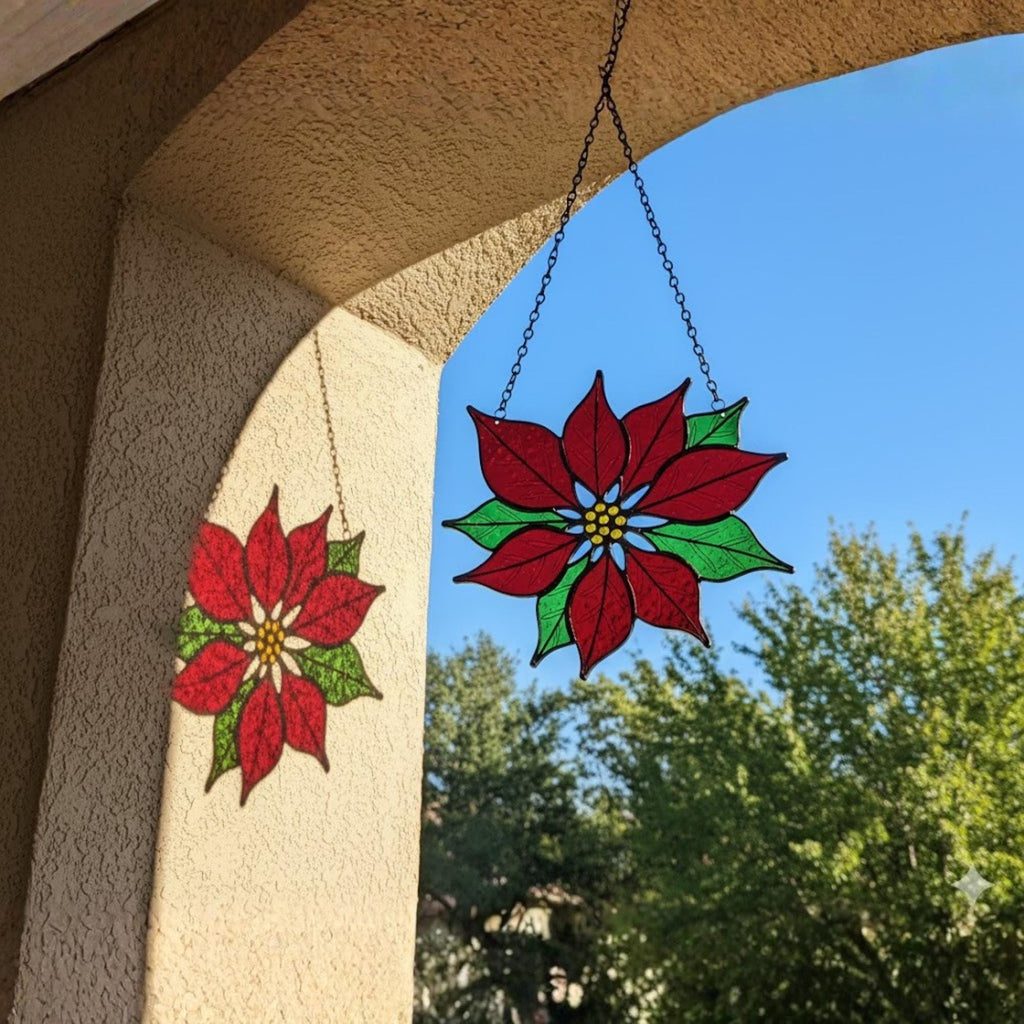 Close-up of handmade stained glass poinsettia suncatcher in daylight.
