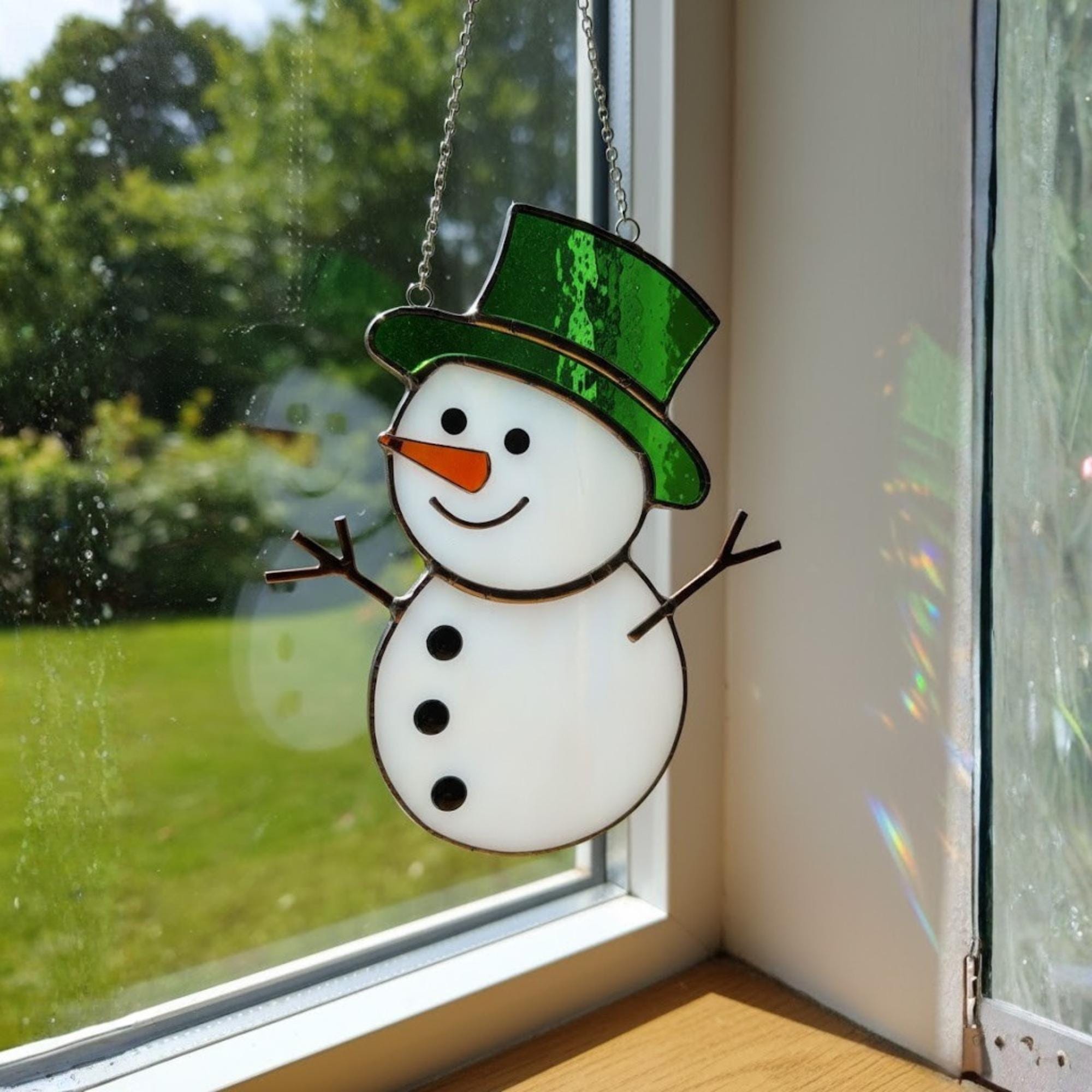Yellow hat stained glass snowman ornament reflecting sunlight beautifully.