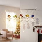 Handmade stained glass snowman ornaments displayed on windowsill in sunlight.