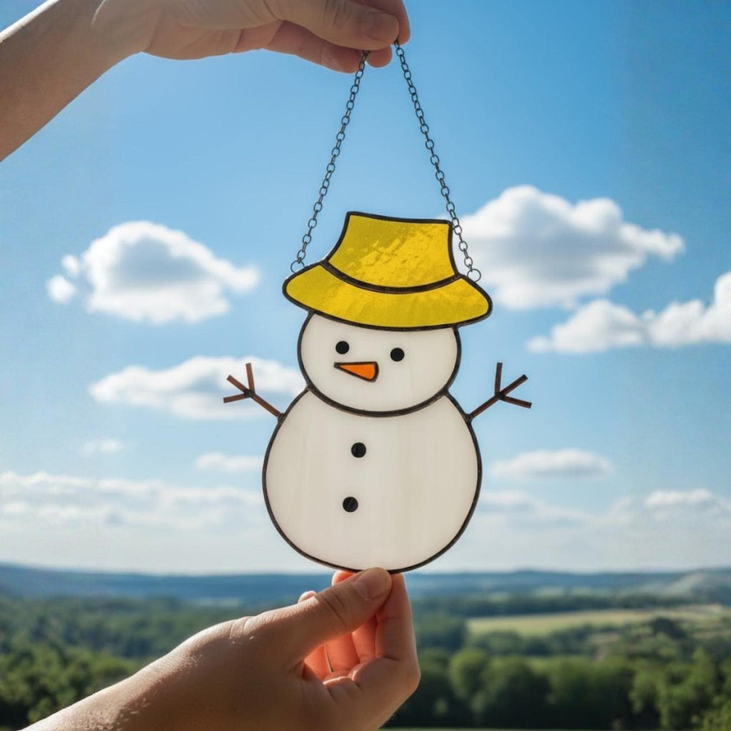 Close-up of colorful stained glass snowman with yellow hat shining in daylight.
