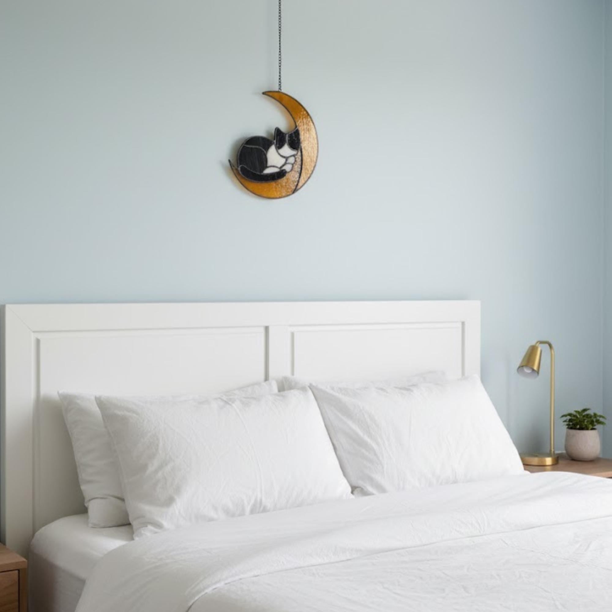 Cat on the moon stained glass window ornament glowing in afternoon sunlight, artistic home accent