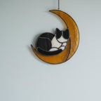Close-up of stained glass cat on moon with trees outside, peaceful celestial decor for windows
