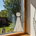 Collection of six stained glass angel designs displayed by the window for home decor.
