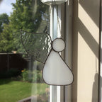 Multiple stained glass angel designs displayed on windowsill for home holiday decoration.