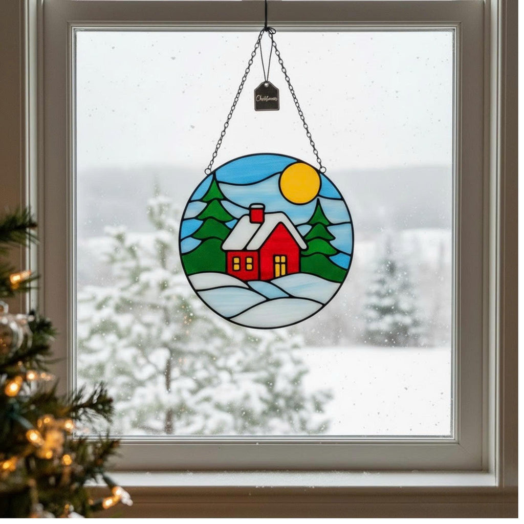 Detailed shot of stained glass winter cottage with golden sun and snow, handmade Christmas suncatcher.
