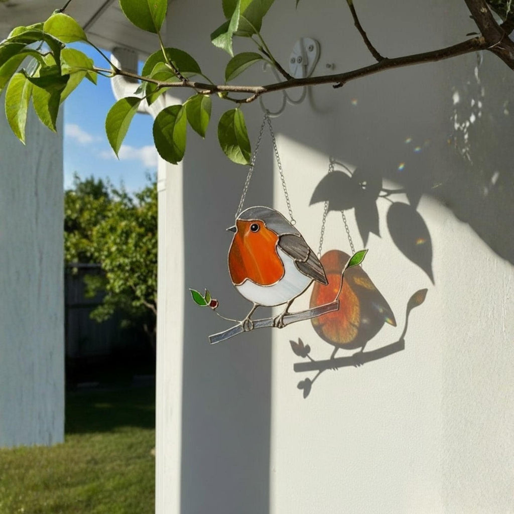 Handmade robin stained glass suncatcher hanging on window, sparkling sunlight bird ornament