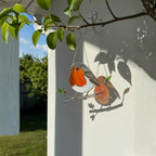 Handmade robin stained glass suncatcher hanging on window, sparkling sunlight bird ornament