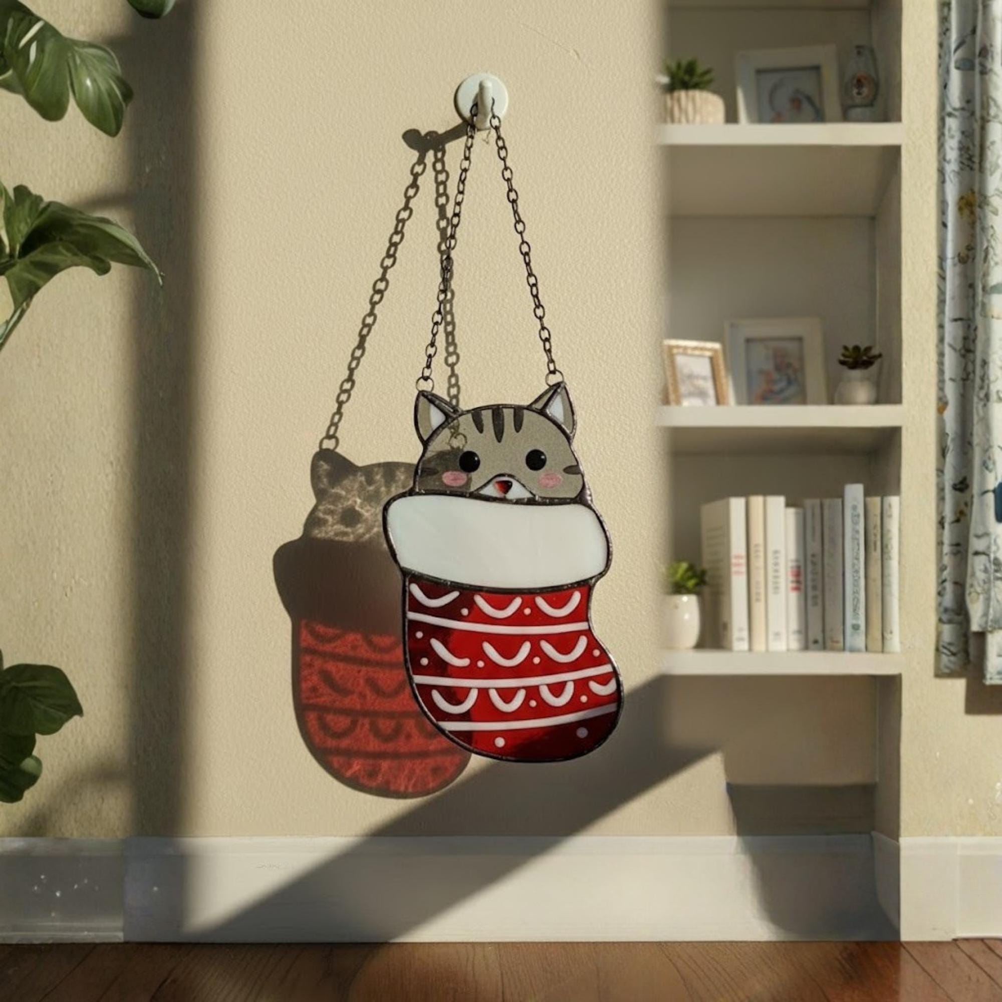 Bedroom window with hanging stained glass Christmas cats, handmade cozy winter decoration.