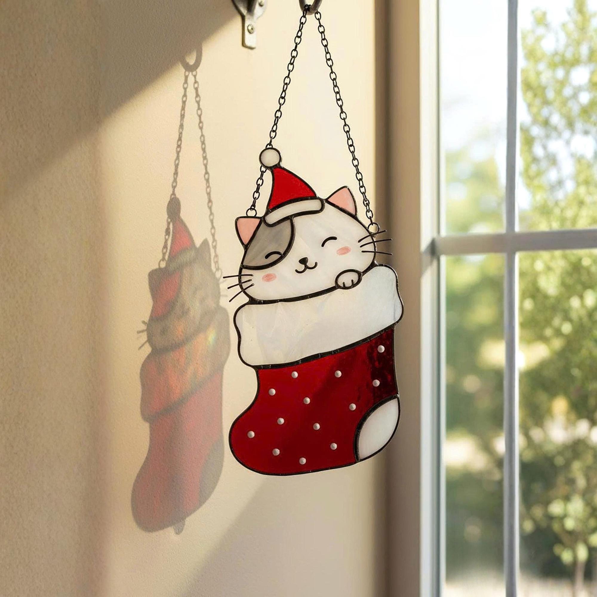 Window view with stained glass cats in stockings glowing in sunlight, festive home decoration.