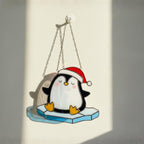 Pair of penguin stained glass ornaments on patio door, sunny garden view