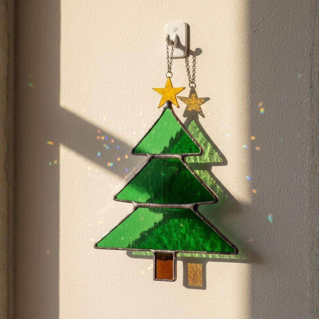 Classic stained glass Christmas tree with star catching sunlight on wall, window ornament