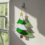 Handmade stained glass Christmas tree suncatcher hanging by window with star topper, winter decor