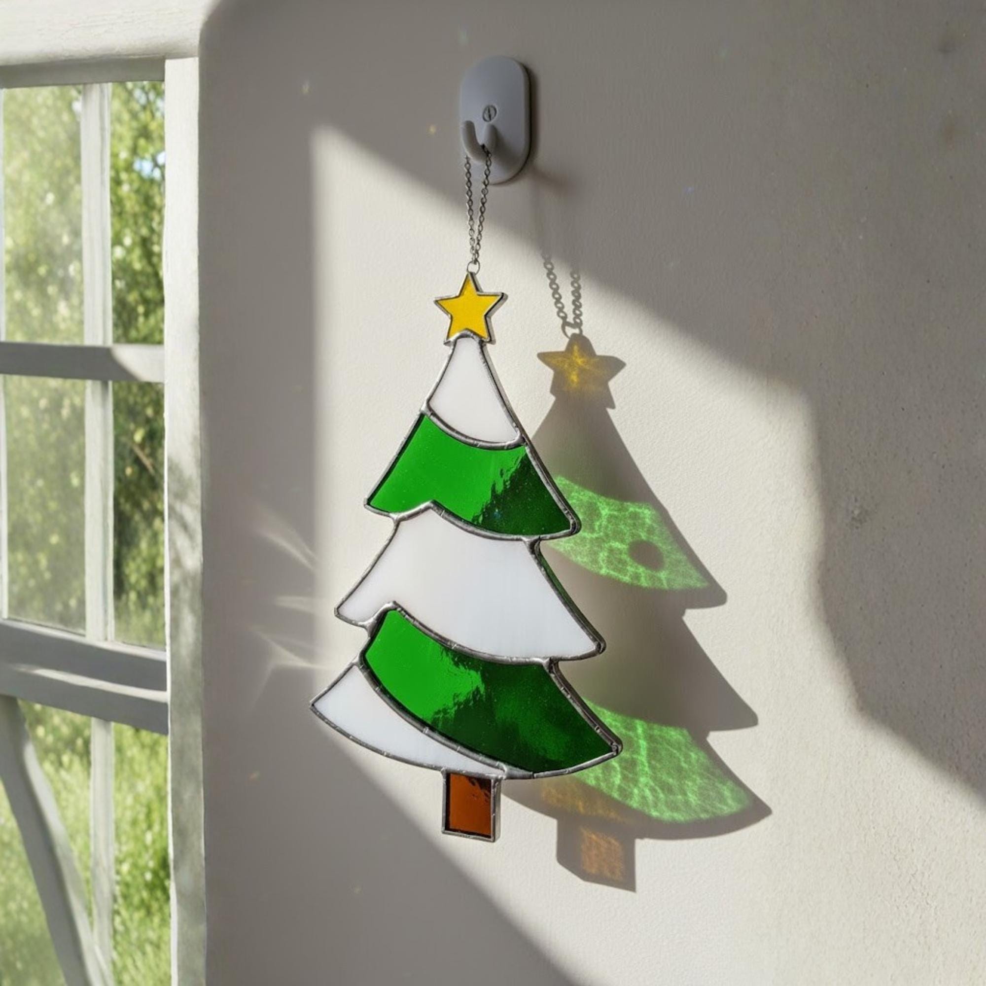 Handmade stained glass Christmas tree suncatcher hanging by window with star topper, winter decor
