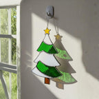 Handmade stained glass Christmas tree suncatcher hanging by window with star topper, winter decor