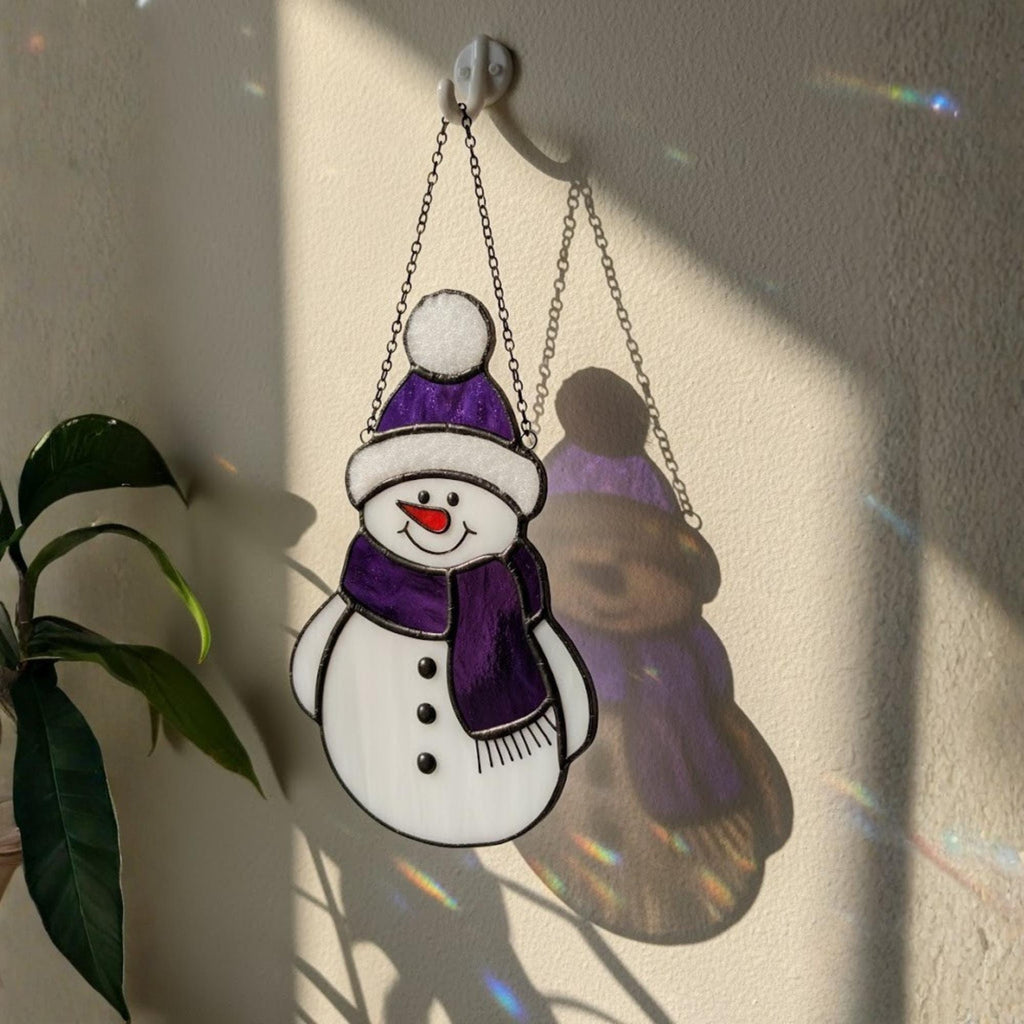 Purple snowman glass ornament hanging indoors – handmade winter window art.