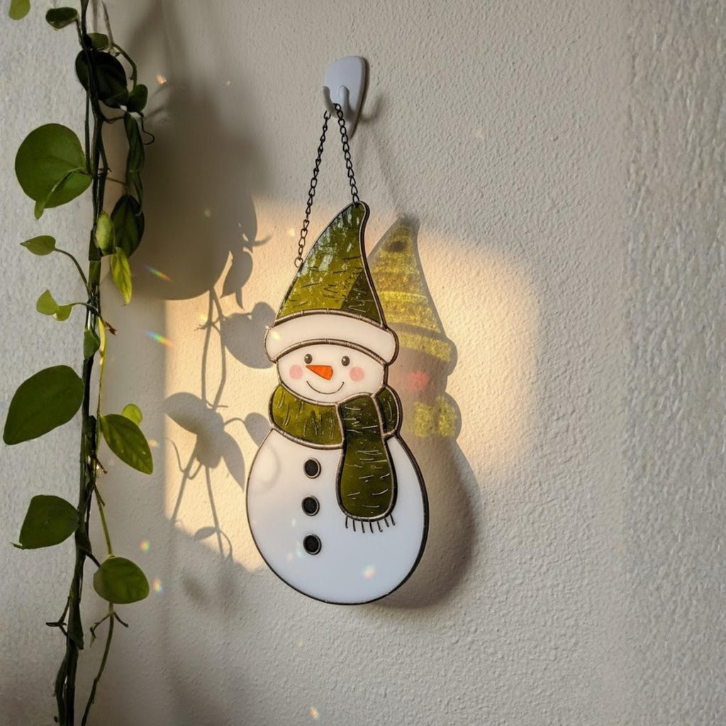Snowman suncatcher glowing on frosted window – cozy winter decoration.
