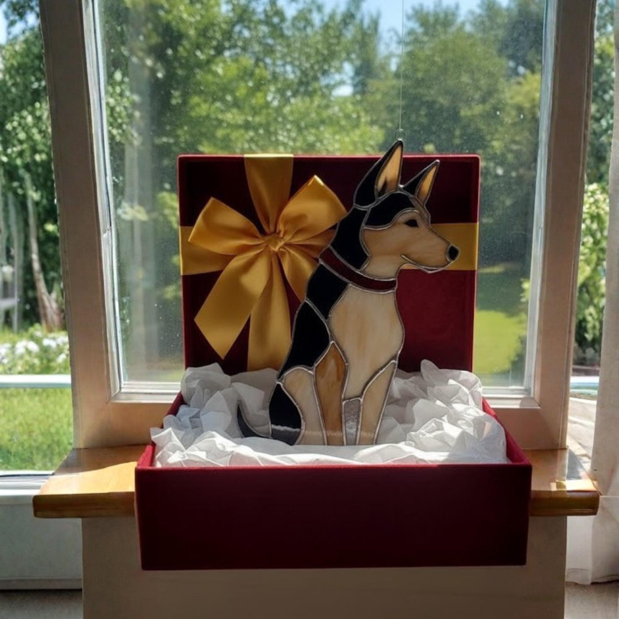 Woman hanging stained glass dog ornament on window, sunlit home decor