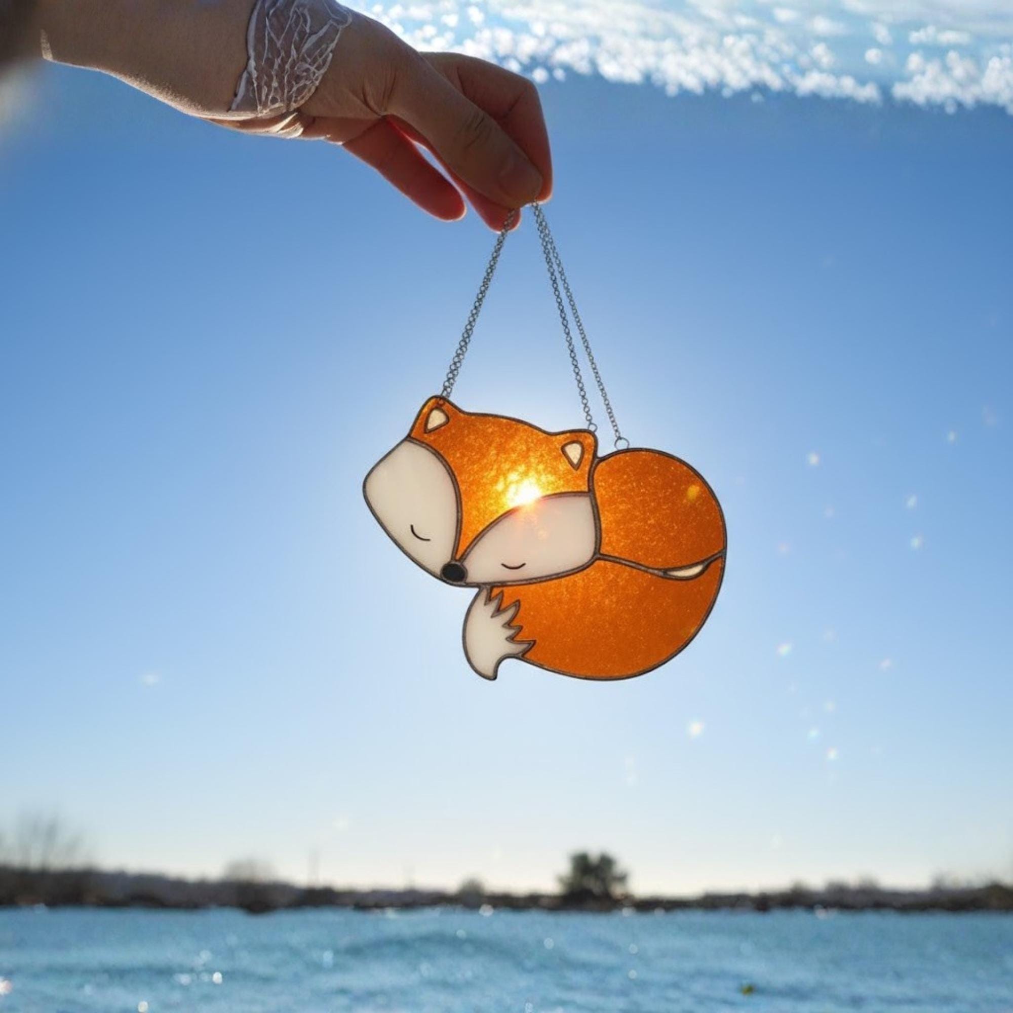 Handmade stained glass fox suncatcher glowing in natural sunlight, cute woodland window decor