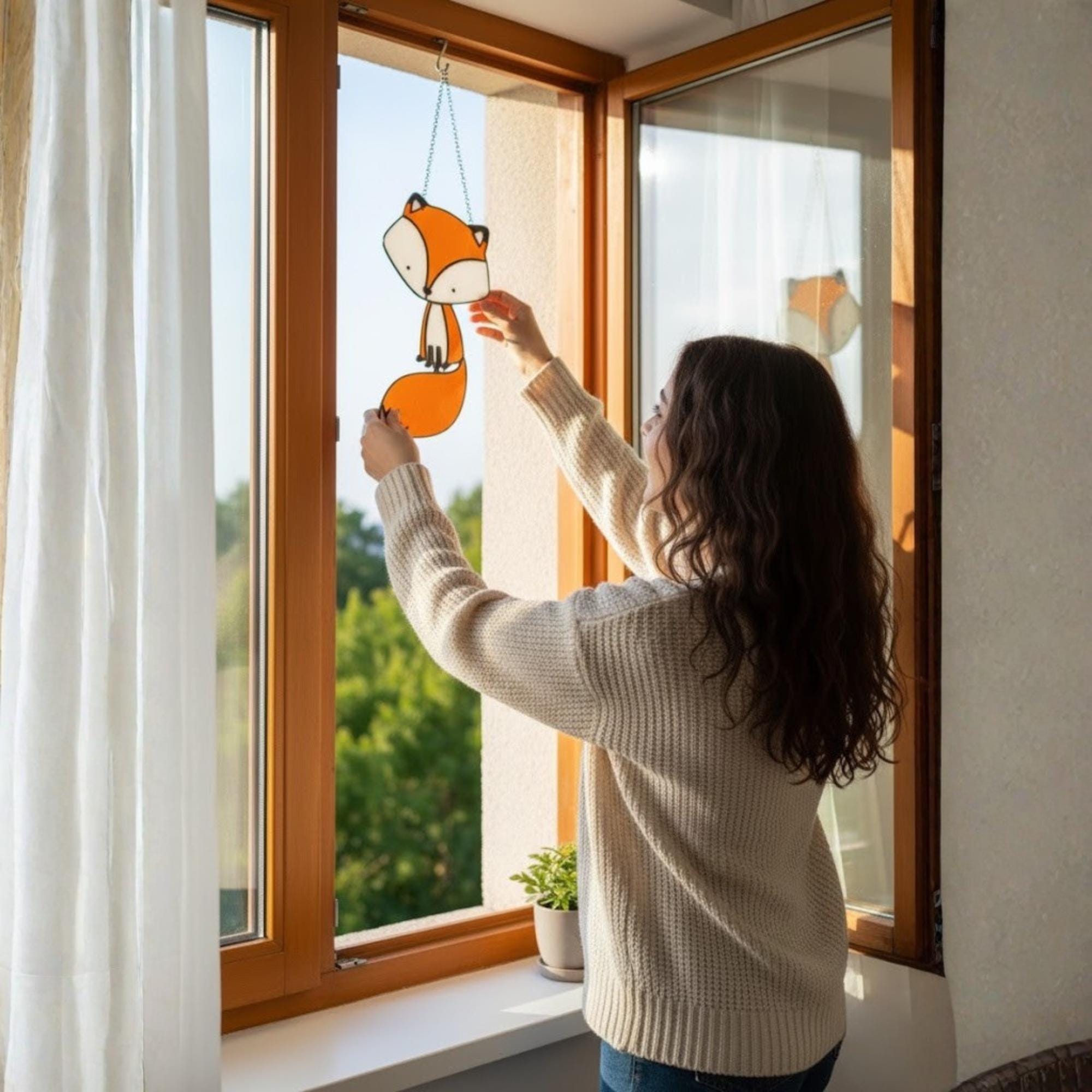 Woman hanging stained glass fox on window, sunlight reflections