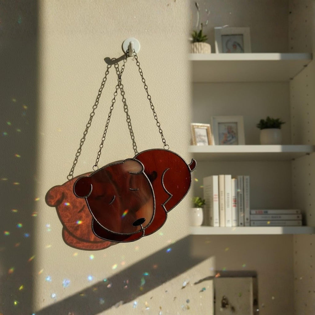 White sleeping dog stained glass ornament glowing in window light