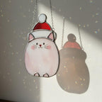 Gray cat suncatcher hanging in bright window light – minimal handmade Christmas decor.