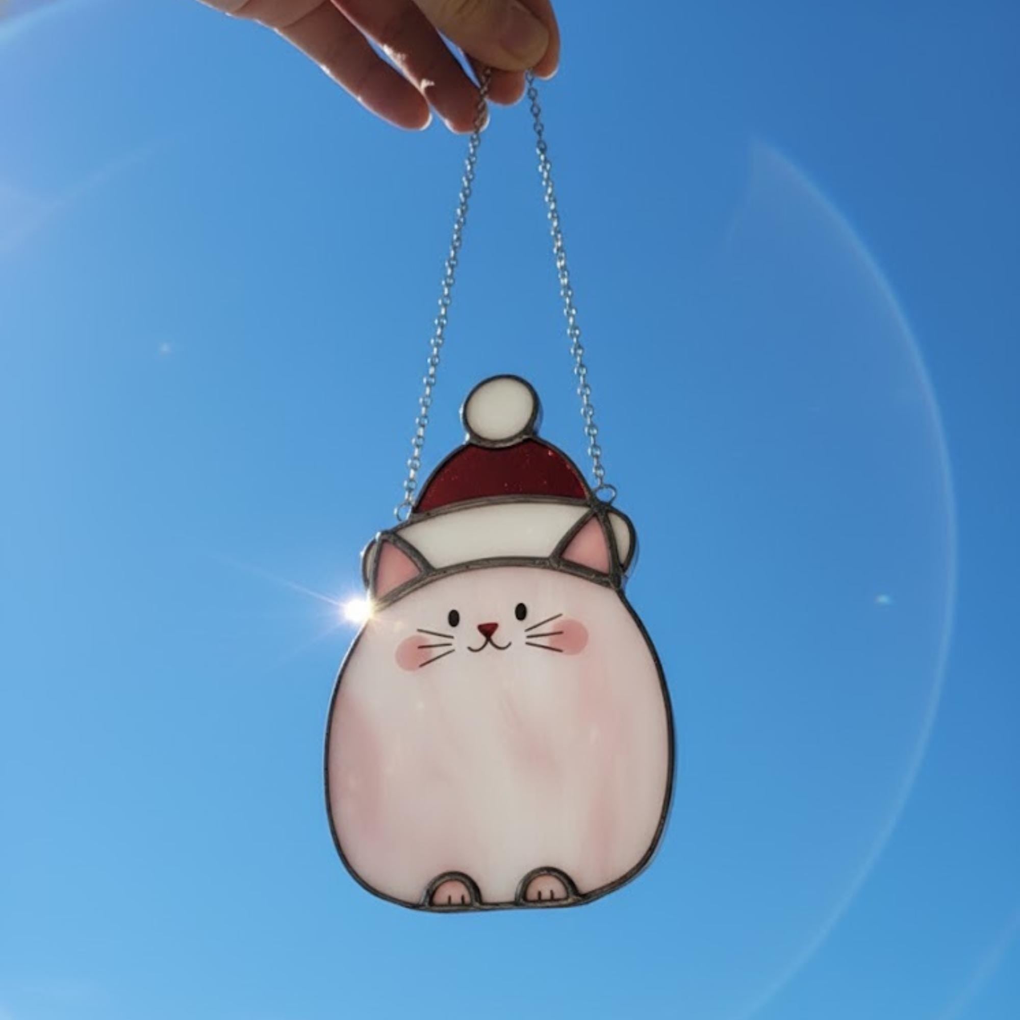 Blue sky behind cute cat glass ornament – cheerful holiday window suncatcher.
