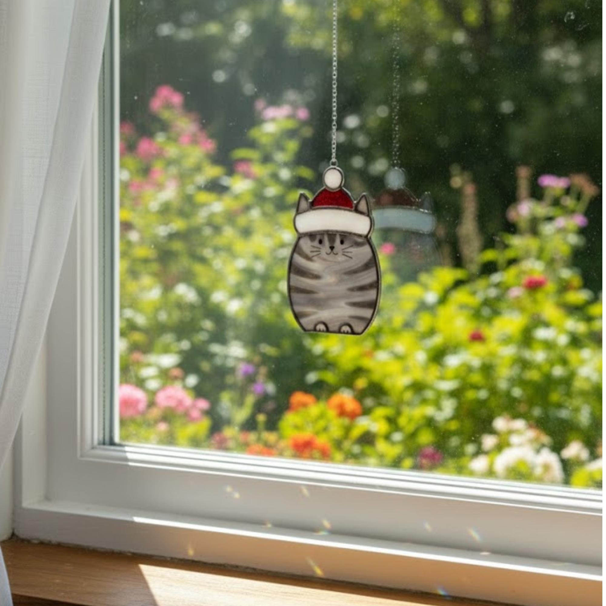 Close-up of stained glass cat ornaments glowing under blue sky – handmade glass art gift.