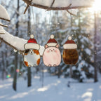 Cat suncatcher ornaments glowing on window in winter sunlight – festive home decor piece.