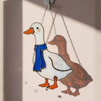 Stained glass goose hanging on window with warm afternoon light, handmade décor